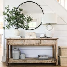 a wooden table sitting under a mirror next to a stair case