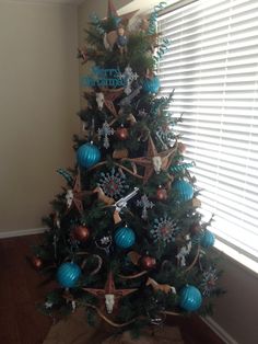 a decorated christmas tree with blue and gold ornaments on it in front of a window