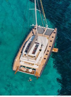 an aerial view of a sailboat in the ocean with clear blue water around it