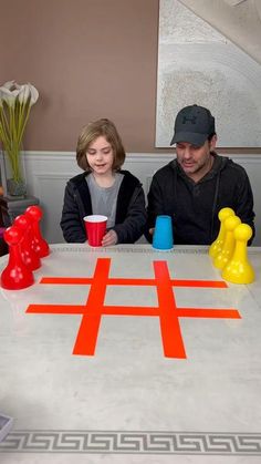 a man and child sitting at a table with an orange game board on top of it