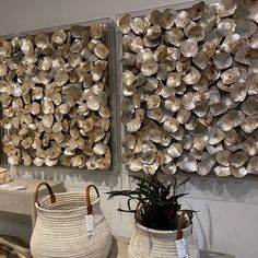 two baskets are sitting next to each other in front of large metal wall art pieces