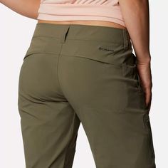 a woman wearing khaki pants and a pink top is looking down at her stomach