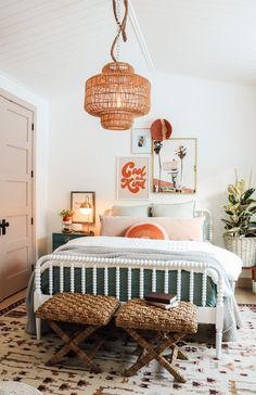 a bedroom with a bed, two stools and pictures on the wall above it