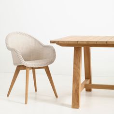 two chairs and a table in front of a white wall, one with a wooden top