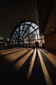 people are walking through an airport terminal with their shadows cast on the floor and walls