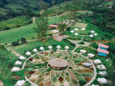 an aerial view of a circular structure in the middle of a lush green field with trees