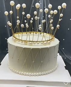 a white cake with pearls and gold decorations