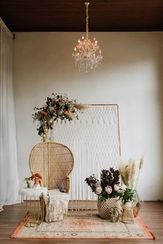 a room with a chandelier and flowers on the floor next to a wicker chair