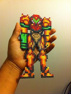 a hand holding up a small pixel art piece in the shape of an ornament