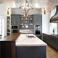 a large kitchen with marble counter tops and stainless steel appliances, along with an island in the middle