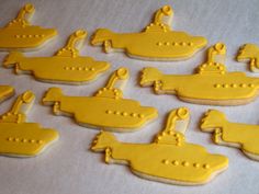 decorated cookies with yellow icing depicting a submarine and other ships on a white tablecloth