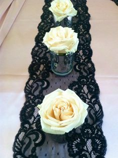 two vases with roses are sitting on a lace table runner that's lined up