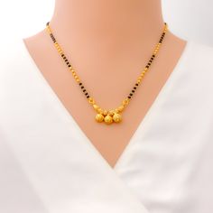 This 22k gold mangal sutra, weighing 9.1 grams, boasts a striking combination of traditional design and modern elegance. Its black bead accents complement the yellow gold finish, while the 16-inch necklace length ensures a graceful fit. The 0.25-inch drop adds a subtle yet captivating detail, and the secure hook lock offers both comfort and convenience. Perfect for symbolizing marital unity with a contemporary twist, this piece is ideal for any special occasion, blending cultural significance with timeless beauty. PRODUCT DETAILS Gold Purity(karat): 22k Item Weight(grams): 9.1 Item Finish: Yellow Gold Stone: Black Bead Necklace Length: 16" Drop Length: 0.25" Lock Style: Hook Lock Gold Necklace With Black Beads For Puja, Gold Jewelry With Black Beads For Puja, Elegant Yellow Necklace For Puja, Traditional Gold Necklace With Black Beads, Traditional Yellow Gold Jewelry With Black Beads, Festive Black Necklace With Gold Beads, Elegant Black Temple Necklace As Gift, Elegant Black Temple Necklace Gift, Gold Necklaces With Black Beads For Festivals