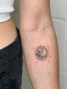 a woman's arm with a small globe tattoo on it