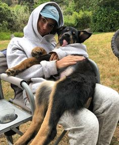 a person sitting in a chair with two dogs on their lap and one is holding the dog