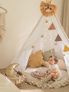 a baby sitting in a teepee with lights on it