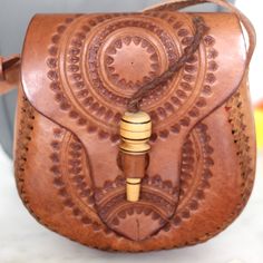 This beautiful sol design leather bag is hand-tooled by our artisan partner Daniel & family at his home work shop in Chiapas, Mexico. Each bag is individually hand-tooled onto quality thick leather, small variations in design and color can occur. Details: Can be worn over the shoulder or cross bodied. Adjustable strap for length- 55” 7 inch L x 8 inch H Wooden closure 100% Pure and Thick Cow Leather. All items are shipped from US Due to the handmade nature and the rawness of the leather, each ba Artisan Hand Tooled Shoulder Bag For Travel, Artisan Satchel With Adjustable Strap, Traditional Hand Tooled Satchel For Travel, Traditional Leather Shoulder Bag, Traditional Hand-tooled Satchel For Travel, Artisan Hand-tooled Shoulder Bag For Festivals, Traditional Leather Satchel With Adjustable Strap, Traditional Hand Tooled Shoulder Bag As A Gift, Artisan Hand Tooled Satchel Shoulder Bag