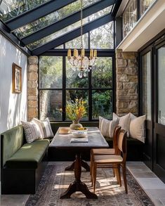 a room with a table, couches and chandelier hanging from the ceiling