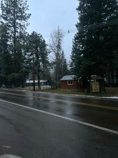 an empty street in the rain with houses and trees