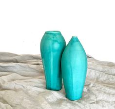 two blue vases sitting on top of a bed