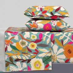 three sheets with colorful flowers on them are stacked next to each other and one is folded up