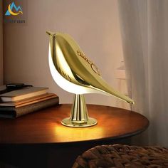 a golden bird lamp sitting on top of a wooden table