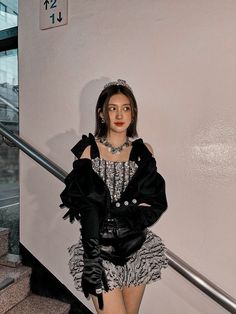 a doll dressed in black and white is standing on the stairs next to a hand rail