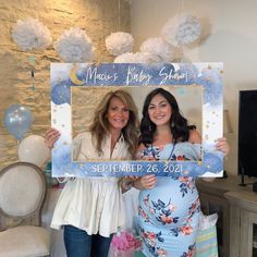 two women standing next to each other holding up a sign