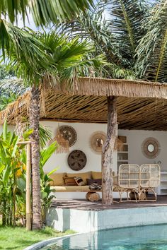 an outdoor living area next to a swimming pool with wicker furniture and palm trees