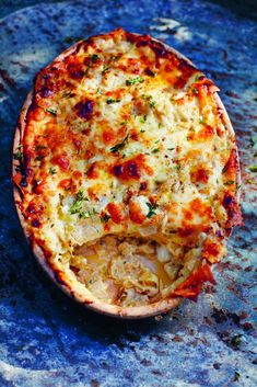 a baked dish with cheese and other toppings sitting on a blue counter top next to a knife