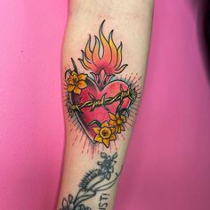 a woman's arm with a heart tattoo on it and flowers in the center