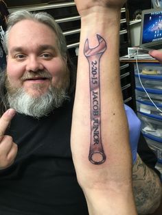 a man with a wrench tattoo on his arm