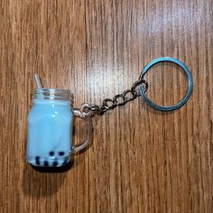 a glass jar with a toothbrush in it sitting on a wooden table next to a metal keychain