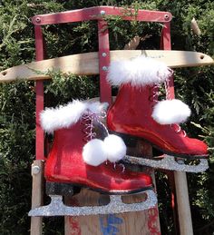 two red snow boots with white pom - poms are attached to a sled