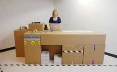 a woman is sitting at a desk made out of cardboard boxes and she's working on her laptop