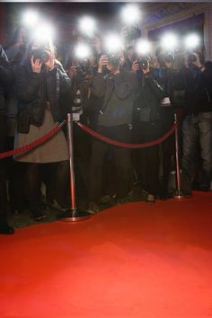 a group of people standing next to each other on top of a red carpeted floor