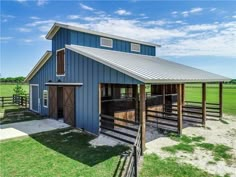 a blue barn with a metal roof and two stalls