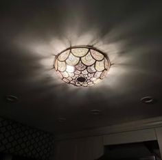 a ceiling light that is hanging from the ceiling in a room with white walls and dark lighting