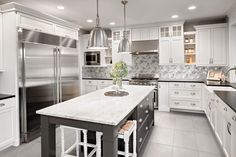 a large kitchen with white cabinets and stainless steel appliances, along with hardwood flooring