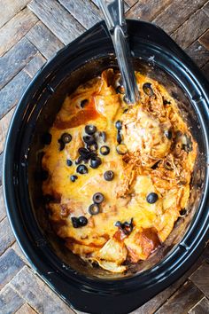 a black crock pot filled with food on top of a wooden table