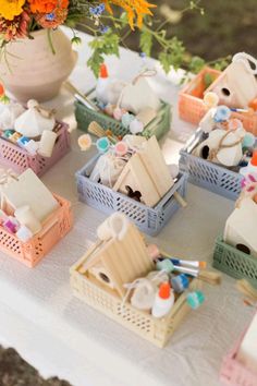 there are many small baskets on the table with flowers in them, and one is filled with doll houses