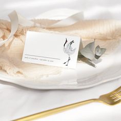 a white plate topped with a piece of paper next to a gold fork and knife