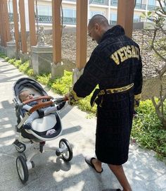 a man in a robe pushing a baby in a stroller