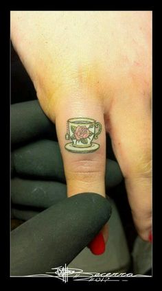 a person with a small tattoo on their left hand and a cup in the middle