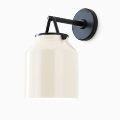 a black and white wall light on a white wall with a round shade hanging from it's side