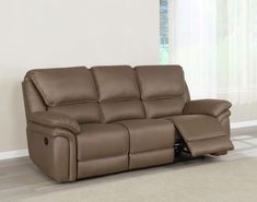 a brown reclining sofa sitting on top of a hard wood floor next to a window