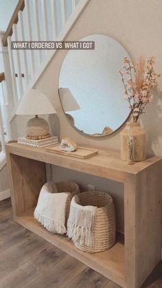 a mirror and some pillows on a wooden shelf in front of a stair case next to a vase with flowers