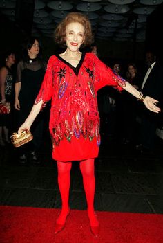 a woman in red is standing on a red carpet with her hands out to the side