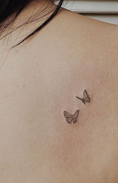 two butterflies on the back of a woman's shoulder