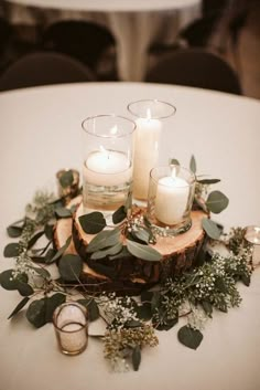 some candles are sitting on a table with greenery